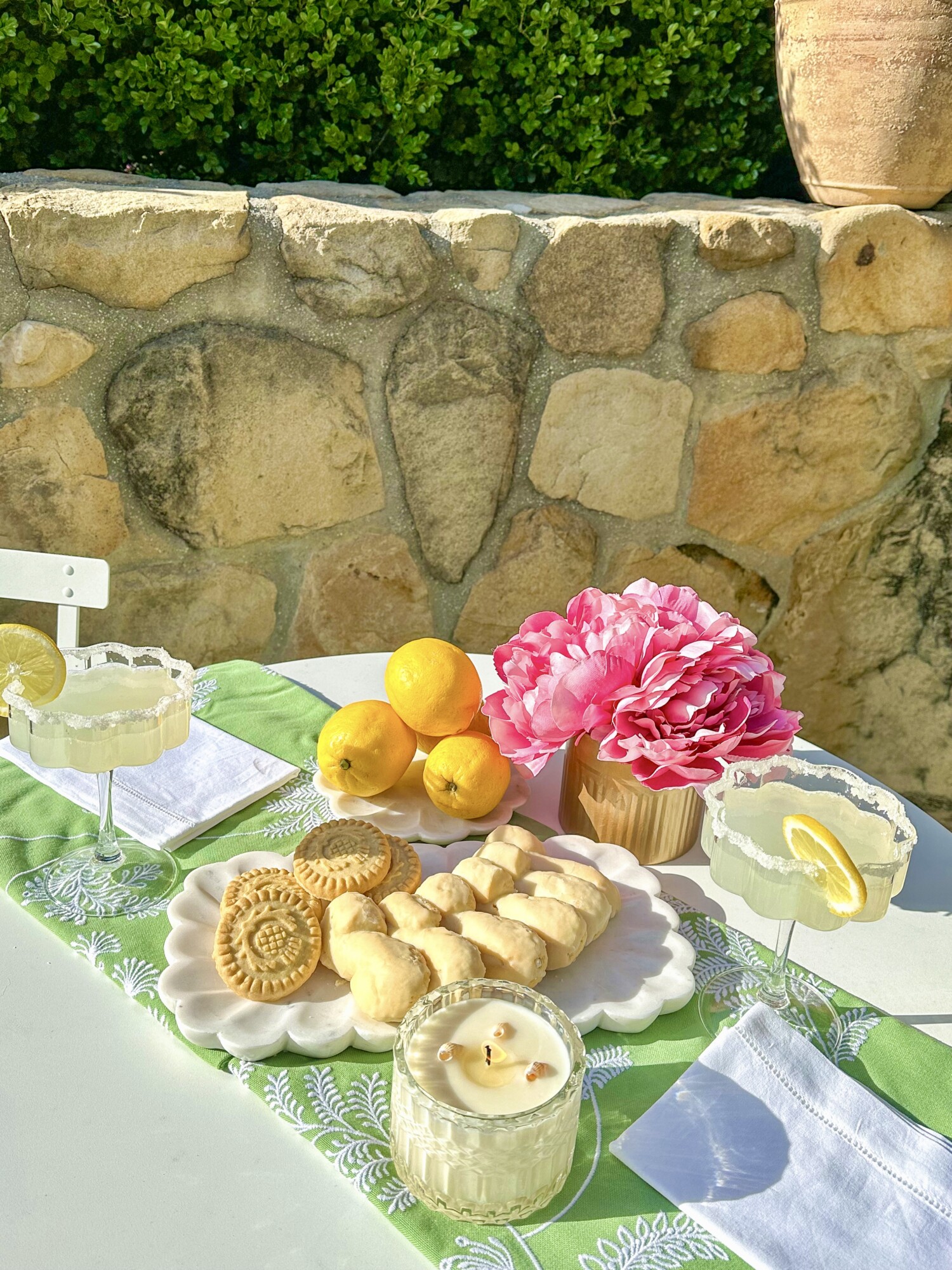 Up-close of drink setup with two lemon drops, candle, green tablecloth